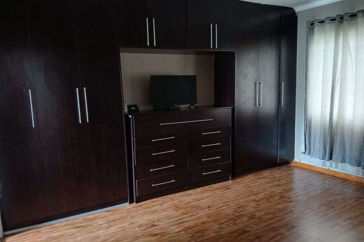 Bedroom featuring extensive dark wood built-in cupboards with integrated storage and durable laminate flooring.