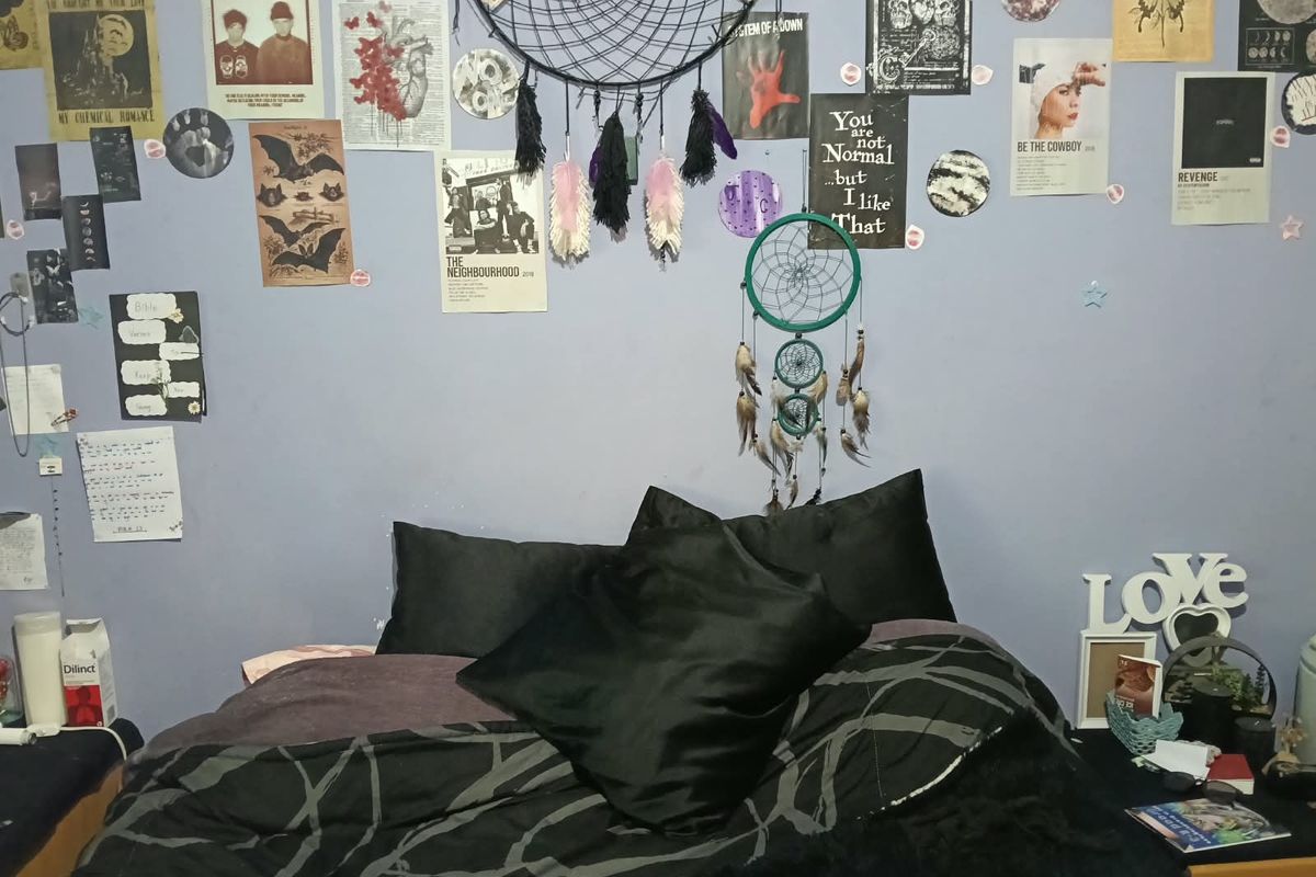 A bedroom featuring a wall with decorative posters and dreamcatchers, providing a personalized space for rest.