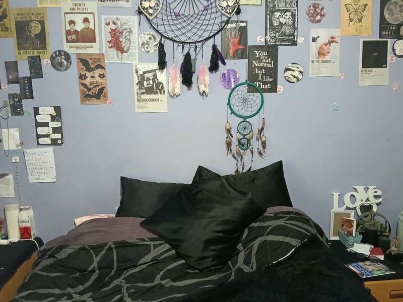 A bedroom featuring a wall with decorative posters and dreamcatchers, providing a personalized space for rest.