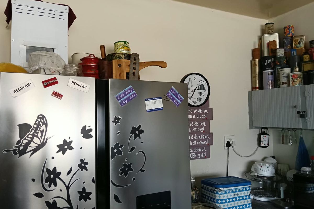 A kitchen corner featuring built-in cabinetry and electrical infrastructure, currently cluttered with various personal items and appliances.
