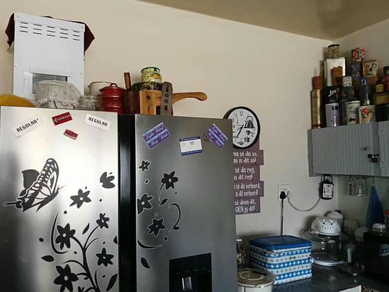 A kitchen corner featuring built-in cabinetry and electrical infrastructure, currently cluttered with various personal items and appliances.