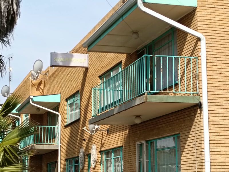 Exterior view of a multi-story apartment building featuring brick facade, metal balcony railings, and integrated downpipes.