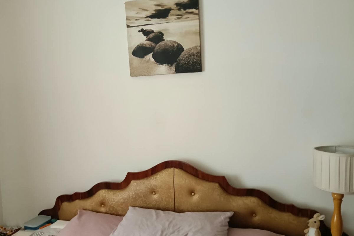 A bedroom interior featuring a decorative headboard and neutral wall finishes.