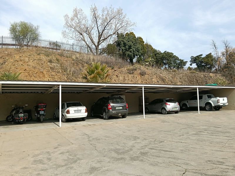 A covered parking area with concrete flooring and metal roofing, providing sheltered space for multiple vehicles.
