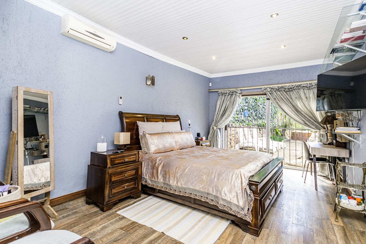 A well-maintained bedroom featuring timber-look flooring, a tongue and groove ceiling, split-system air conditioning, and direct access to an outdoor patio area.