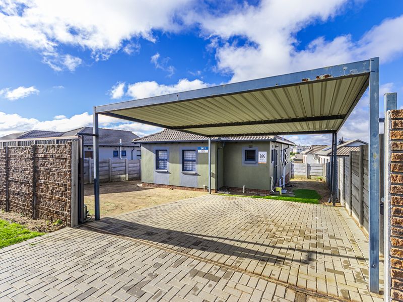 Front exterior view of a residential property featuring a paved driveway, a metal carport, and secure boundary walling.
