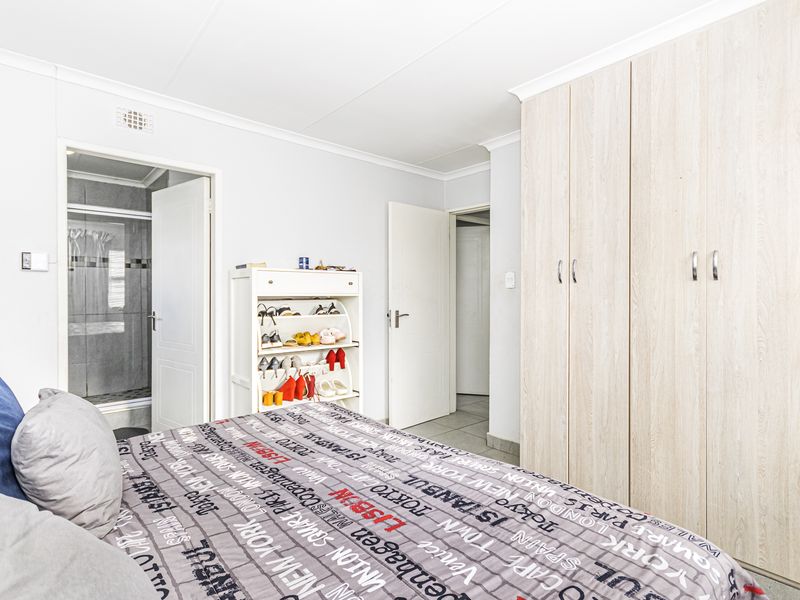A well-maintained bedroom featuring light wood-finish built-in cupboards, coved cornicing, and direct access to an en-suite bathroom.