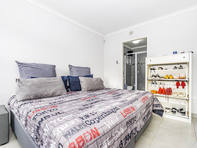 A bedroom featuring tiled flooring and an adjoining en-suite bathroom with a shower enclosure.