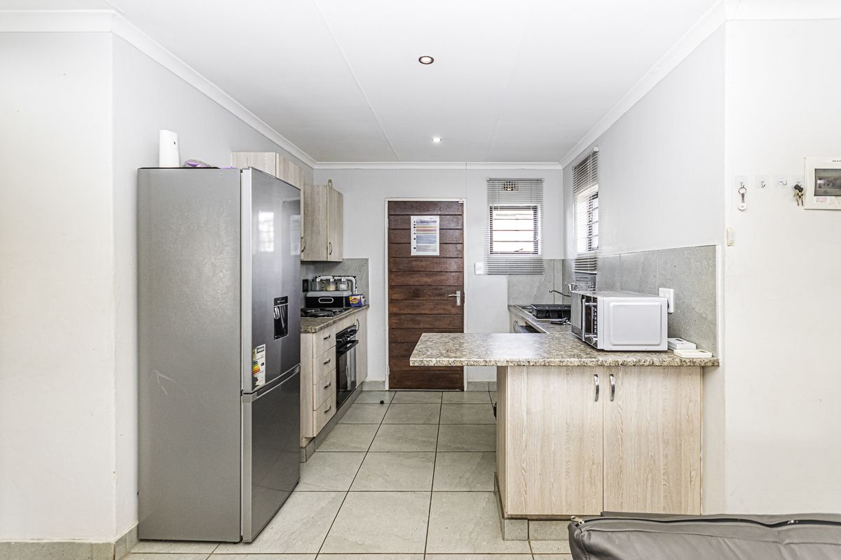 A functional kitchen featuring light wood-finish cabinetry, granite countertops, a breakfast nook, and tiled flooring, providing a practical workspace.