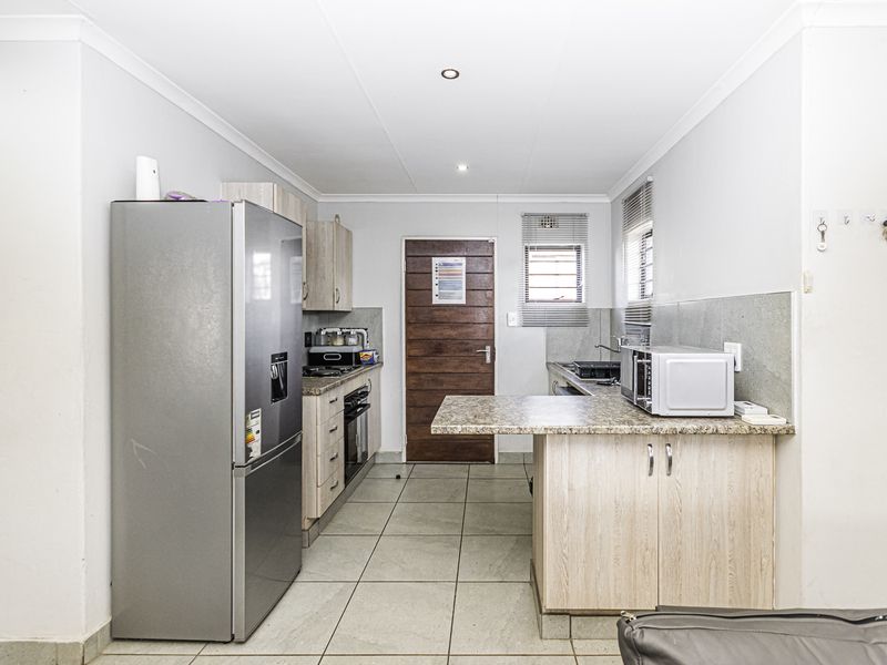 A functional kitchen featuring light wood-finish cabinetry, granite countertops, a breakfast nook, and tiled flooring, providing a practical workspace.