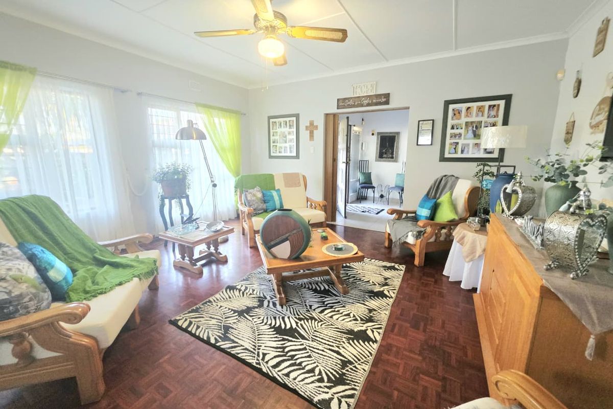 A comfortable living room featuring classic parquet flooring, a ceiling fan, and natural light through sliding glass doors leading to the exterior.