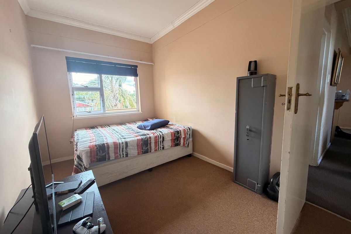 A standard bedroom featuring carpeted flooring, a window with a blind, and neutral wall paint, offering a functional space for rest.