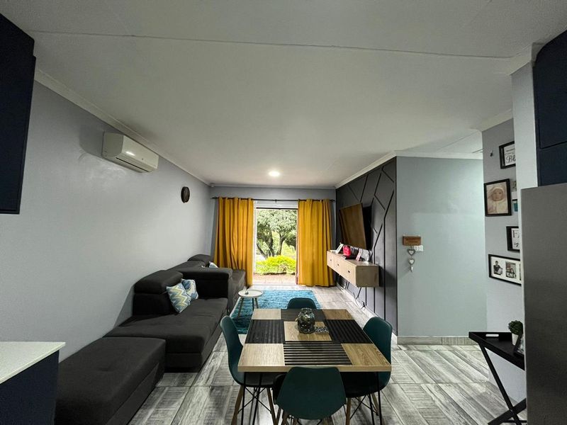 Open-plan living and dining area featuring tiled flooring, a feature wall, and direct access to the outdoor space through sliding doors.