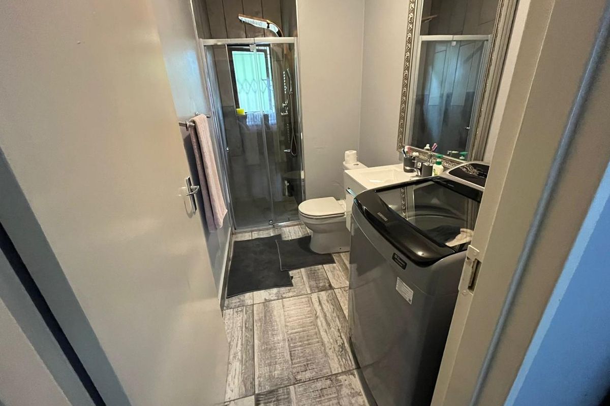 Compact bathroom featuring a shower enclosure, toilet, and vanity basin with modern tiled flooring.
