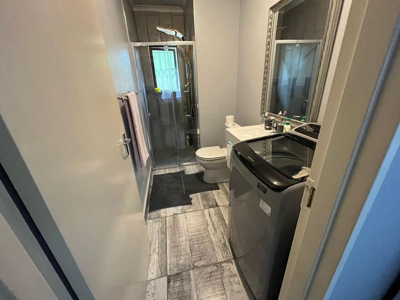 Compact bathroom featuring a shower enclosure, toilet, and vanity basin with modern tiled flooring.