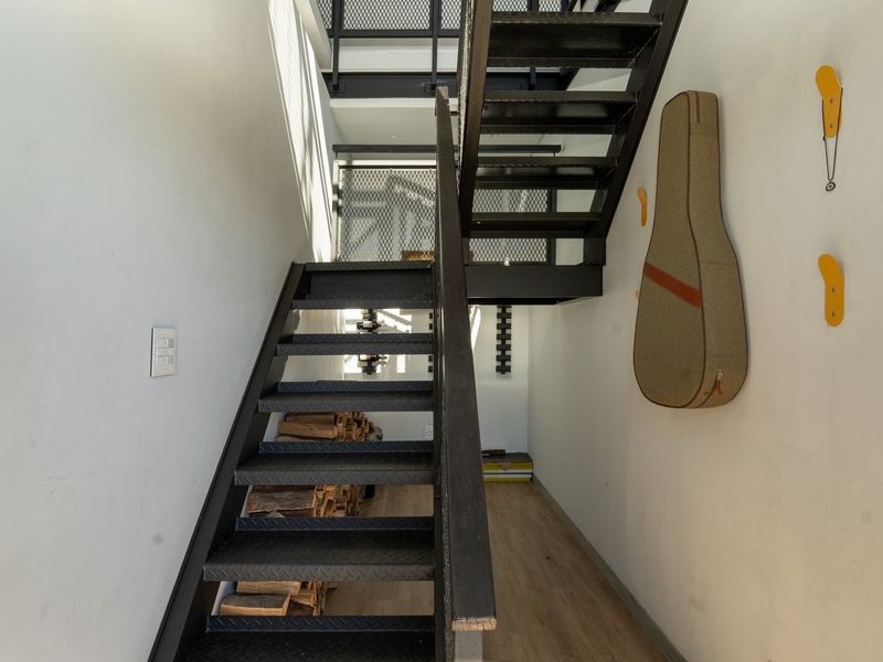 A modern hallway featuring a striking industrial-style black metal staircase with mesh railings and light-toned laminate flooring.