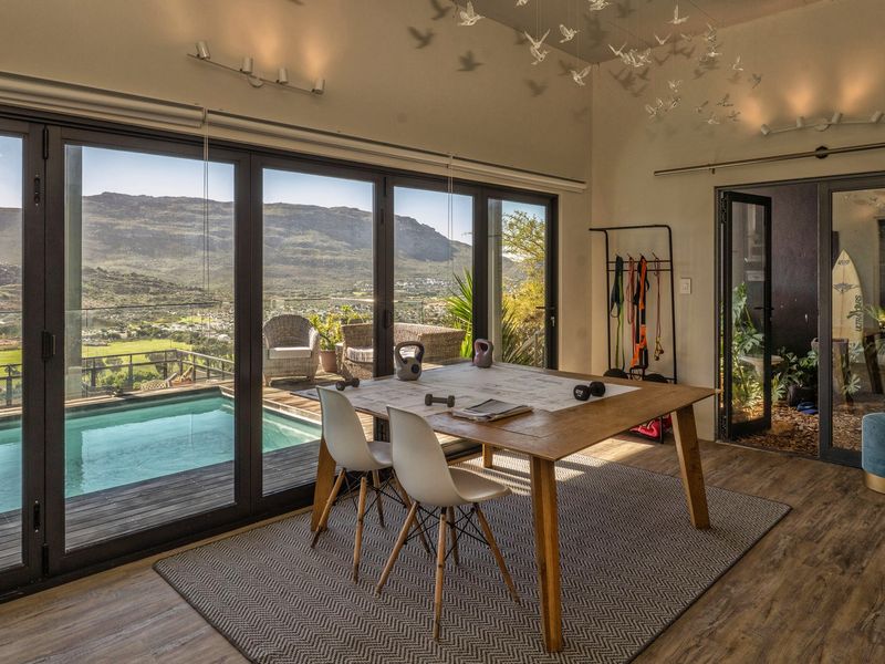 Bright open-plan living space featuring large sliding glass doors that open directly onto a pool deck with scenic mountain views.