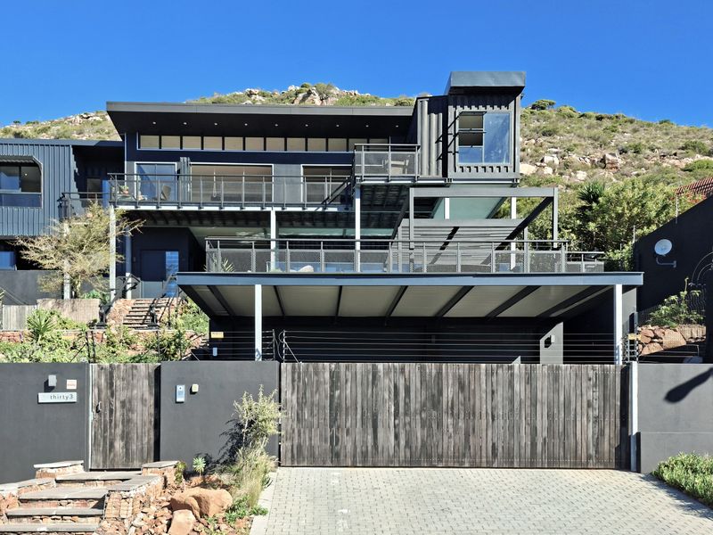 Modern multi-level architectural home featuring dark metal cladding, expansive steel balconies, a covered carport, and secure gated entrance.
