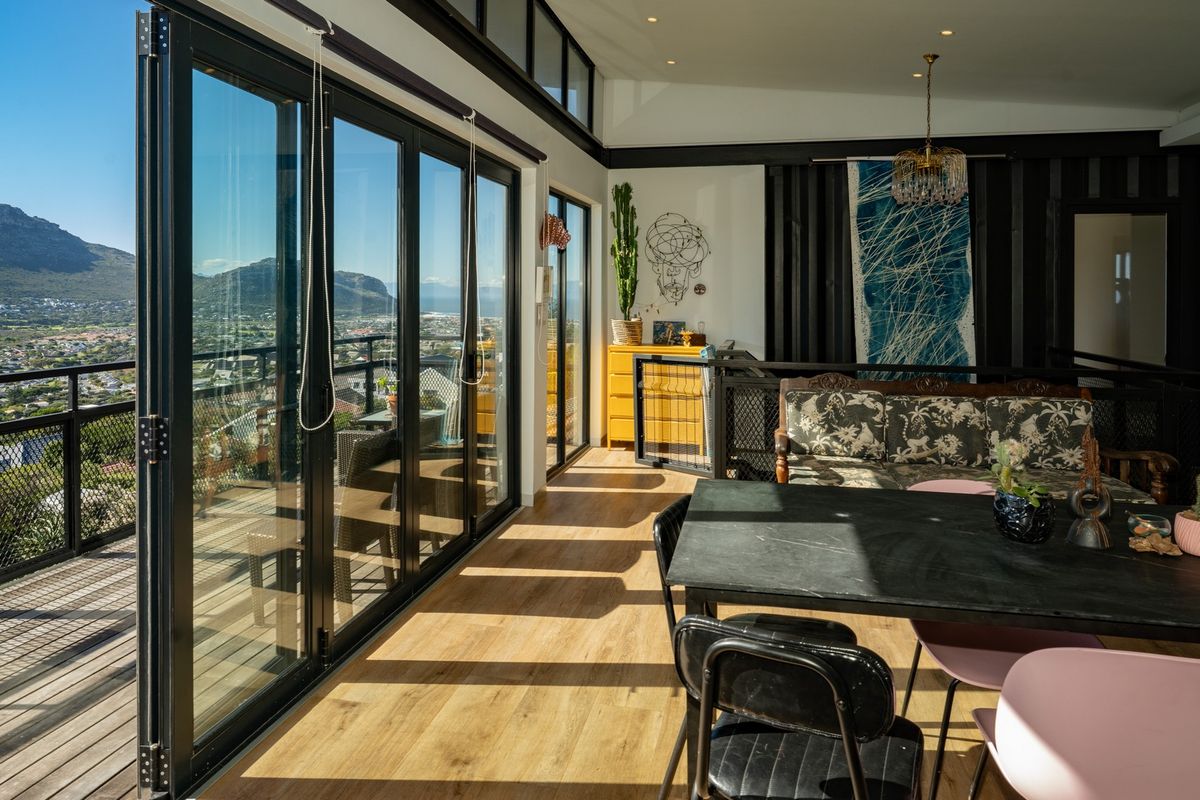 Spacious living area featuring expansive bi-fold glass doors that open onto a timber deck, offering panoramic mountain and valley views with abundant natural light.