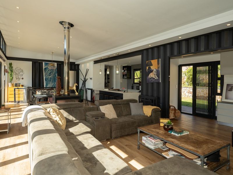 Spacious open-plan living area featuring a modern freestanding fireplace, laminate flooring, and seamless flow to the kitchen and outdoor patio.