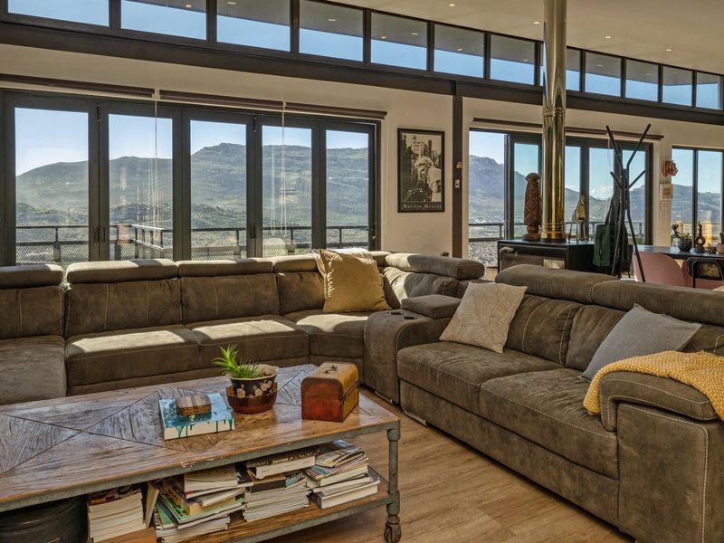 Spacious open-plan living area featuring high ceilings with clerestory windows, a modern freestanding fireplace, and expansive bi-fold doors offering panoramic mountain views.