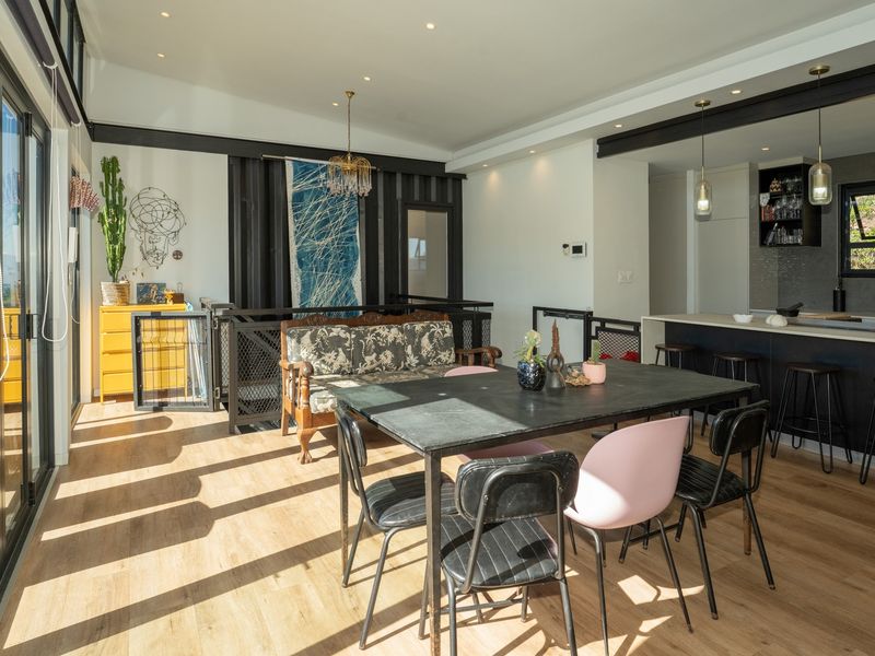 Modern open-plan living and dining area featuring laminate flooring, recessed lighting, a kitchen island, and large sliding glass doors leading to the exterior.
