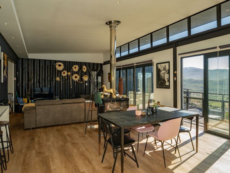 Spacious open-plan living and dining area featuring a modern freestanding fireplace, large sliding doors, and expansive views.