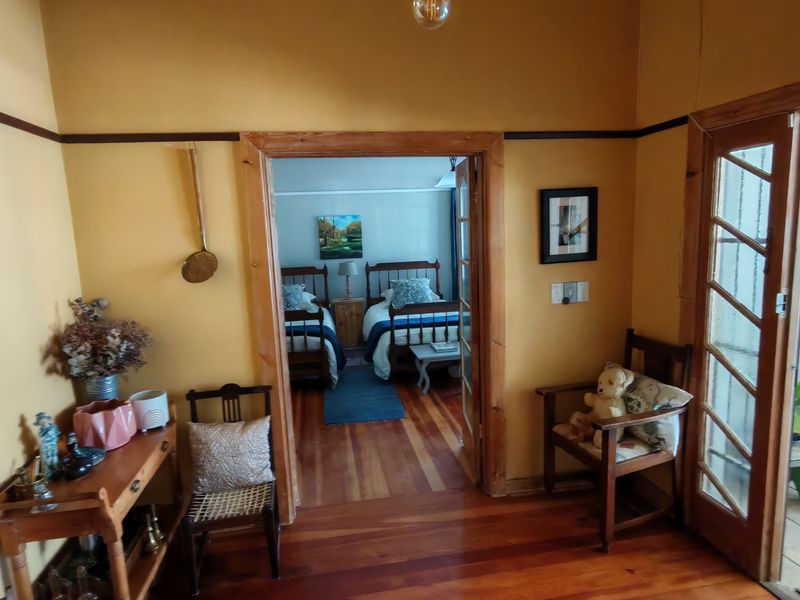 A hallway featuring warm timber flooring and wooden door frames, providing a transition between living spaces and an adjacent bedroom.