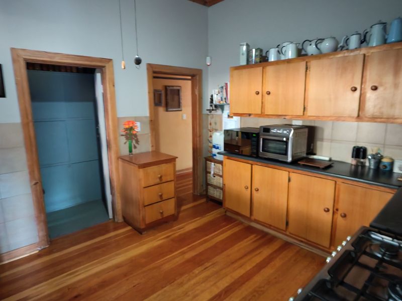 A functional kitchen featuring wooden cabinetry, hardwood flooring, a gas hob, and a built-in oven with a tiled splashback.