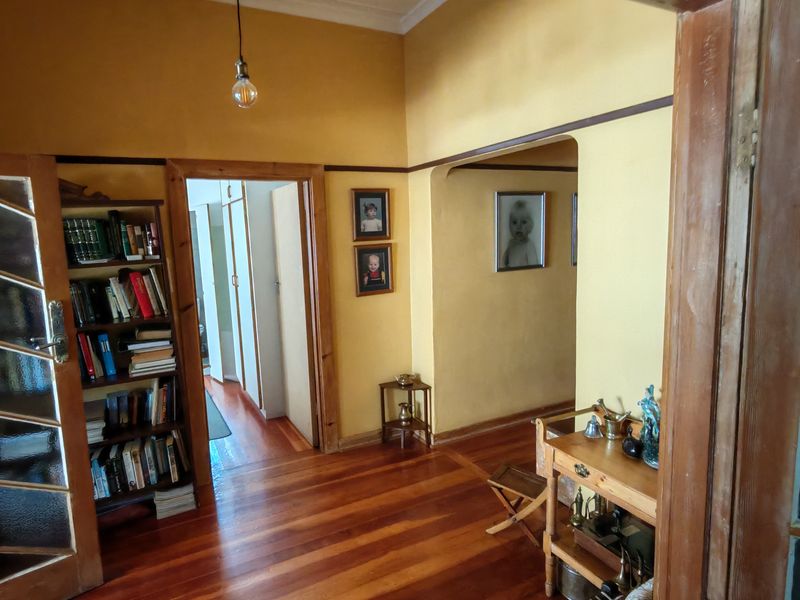 A character-filled hallway featuring warm hardwood flooring, classic timber door frames, and traditional picture rails, connecting multiple living spaces.
