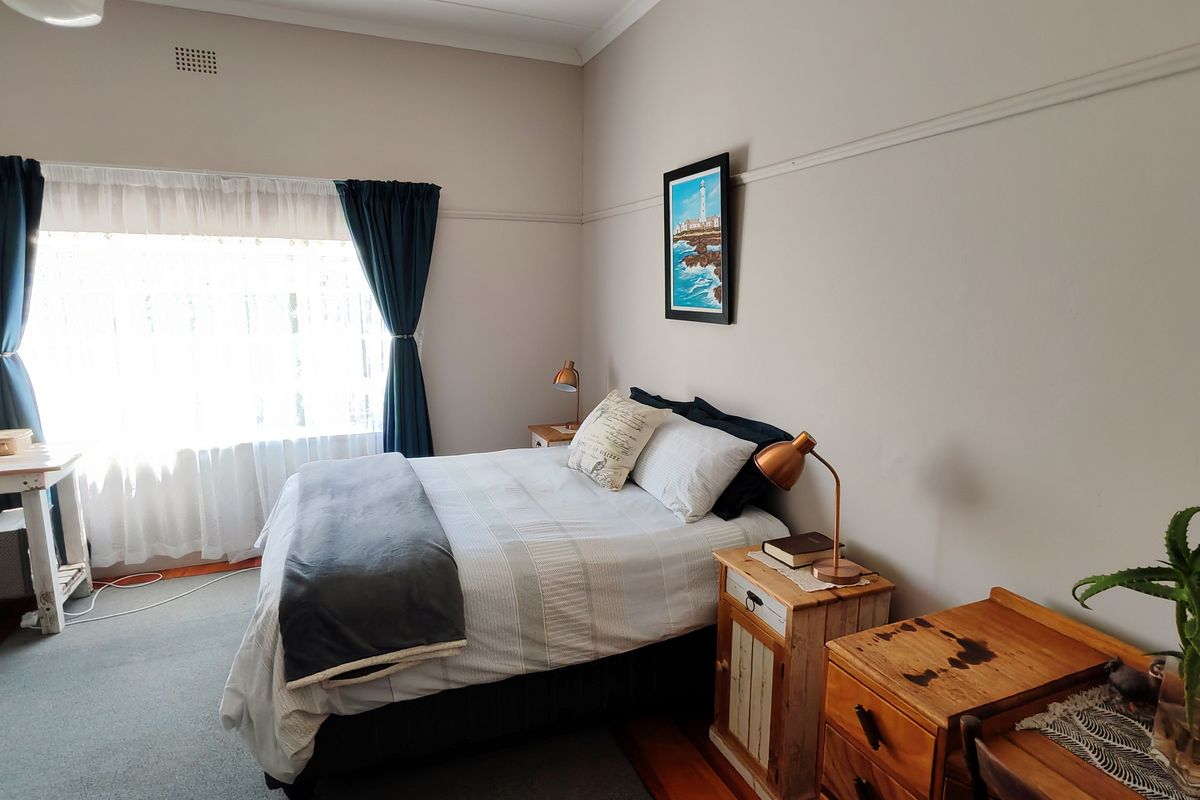 A well-lit bedroom featuring classic picture rails, timber flooring, and a large window with natural light.