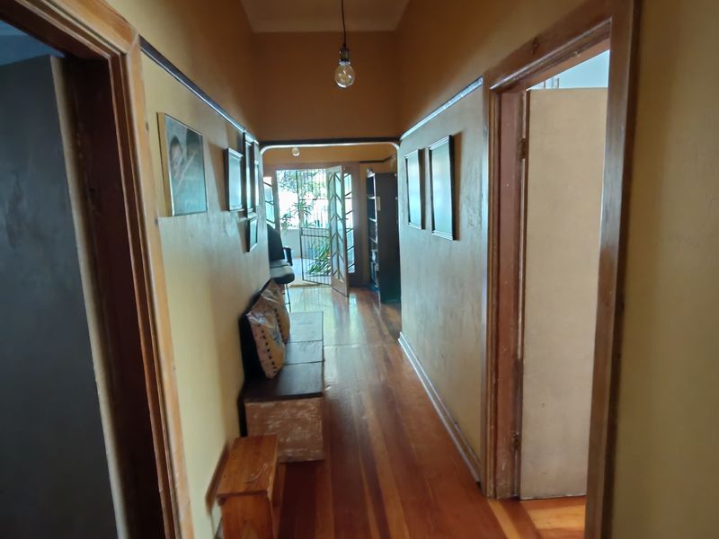 A traditional hallway featuring warm hardwood flooring, timber door frames, and a classic picture rail, connecting various rooms within the home.