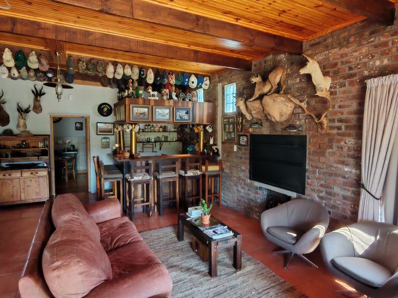 A rustic bar area featuring an exposed brick wall, built-in fireplace, timber ceiling, and tiled flooring, creating a warm and traditional entertainment space.