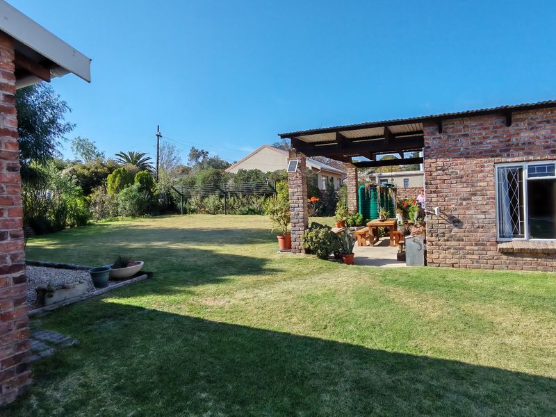 A spacious rear garden featuring a well-maintained lawn and a covered brick patio area, ideal for outdoor relaxation and entertaining.