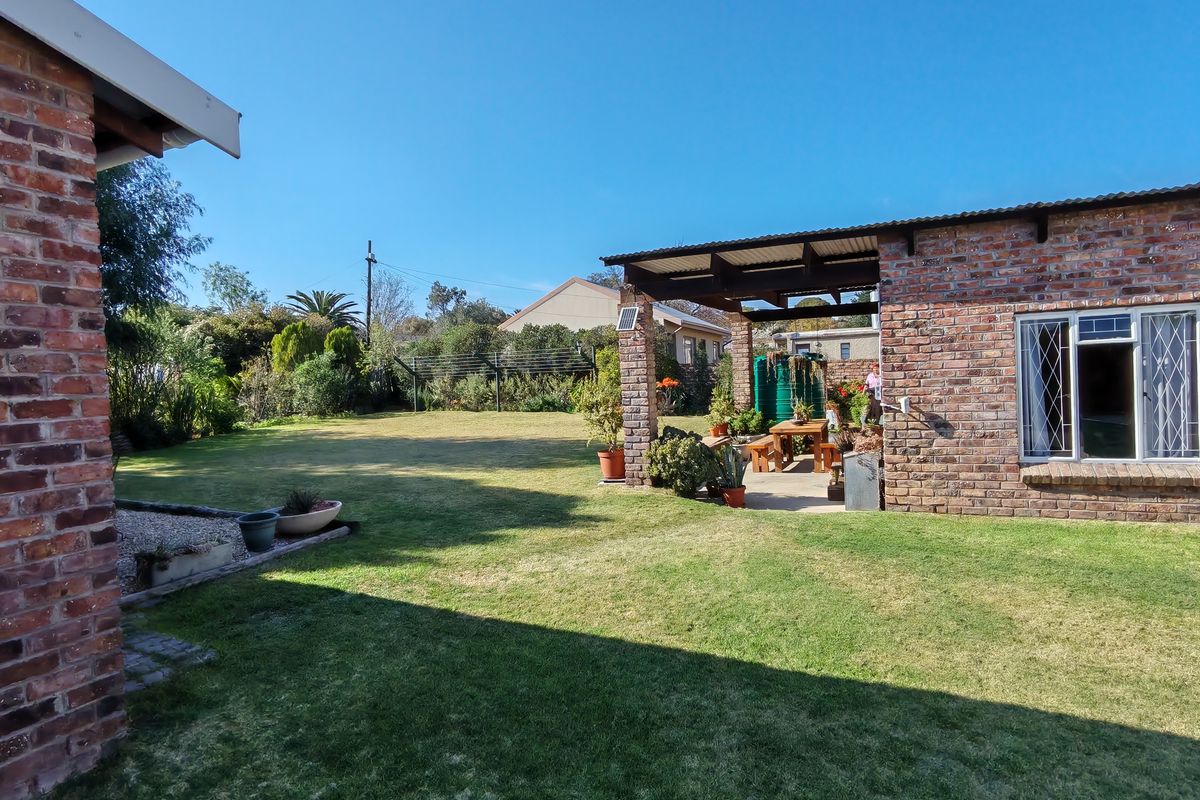 A spacious rear garden featuring a well-maintained lawn and a covered brick patio area, ideal for outdoor relaxation and entertaining.