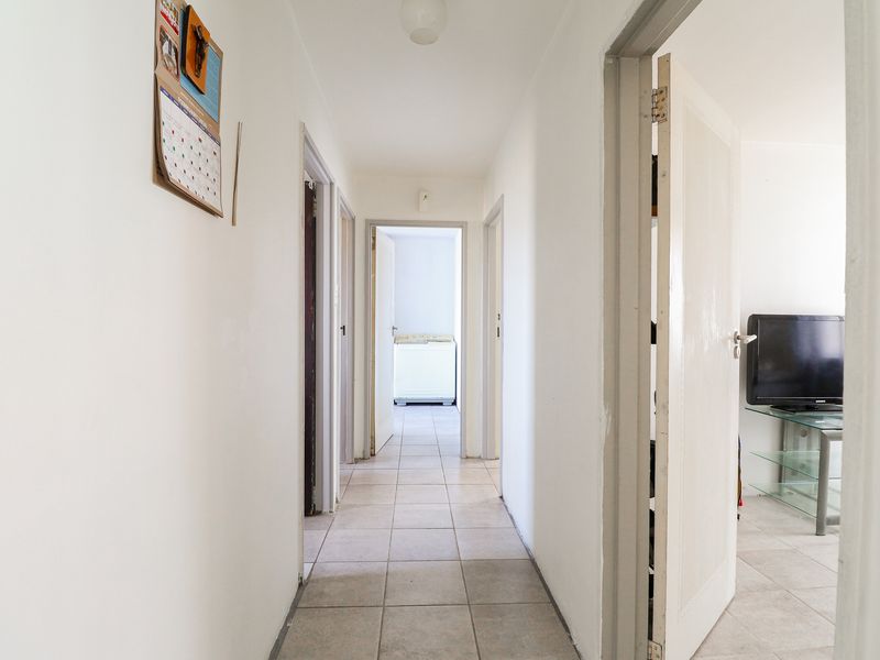 A functional hallway featuring neutral tiled flooring and multiple internal doorways providing access to various rooms within the apartment.