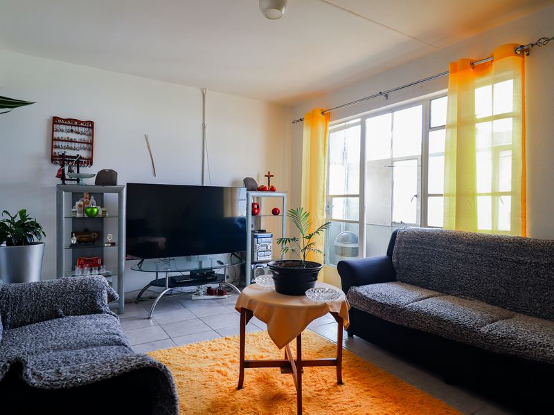 A living room featuring tiled flooring and a large glass sliding door providing natural light and access to the exterior.