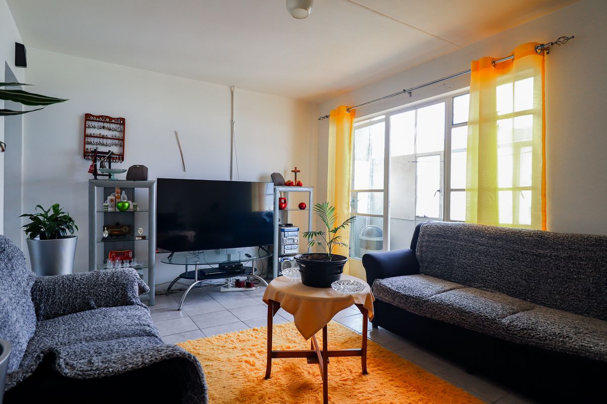 A living room featuring tiled flooring and a large glass sliding door providing natural light and access to the exterior.