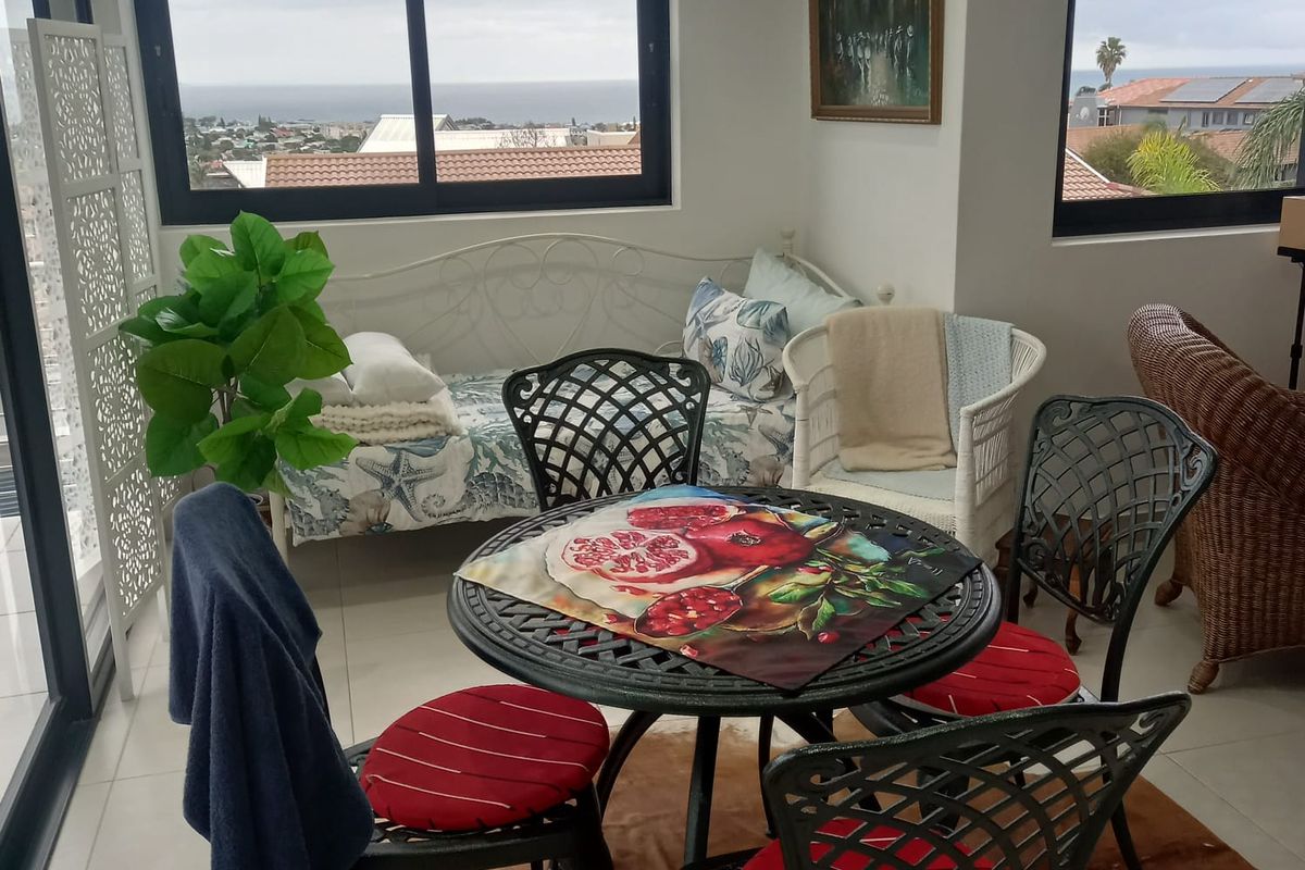 A bright living area featuring large windows with coastal views, tiled flooring, and sliding glass door access to an outdoor space.