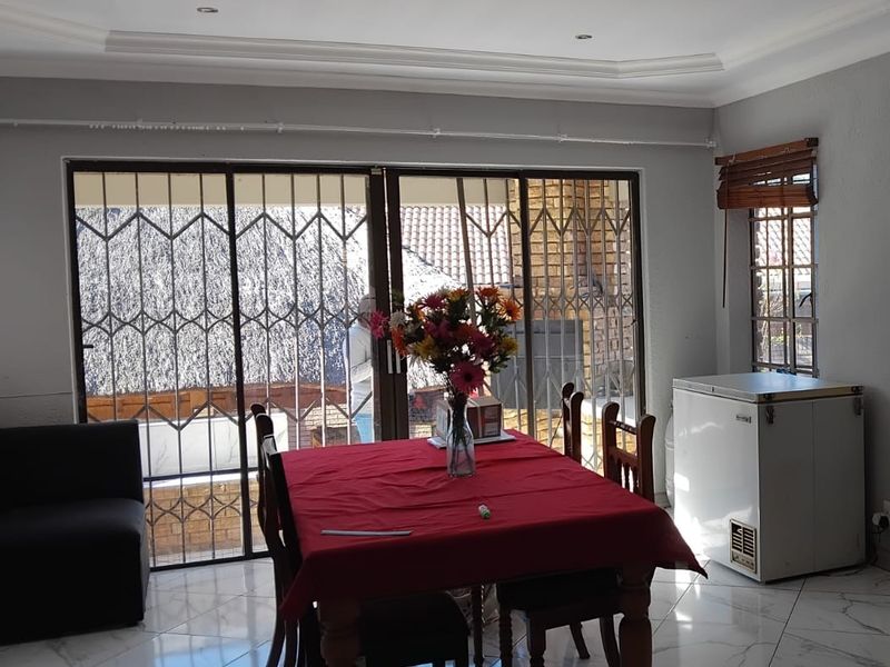 Dining area featuring tiled flooring, coved ceilings, and large sliding glass doors with security gates providing access to the outdoor space.