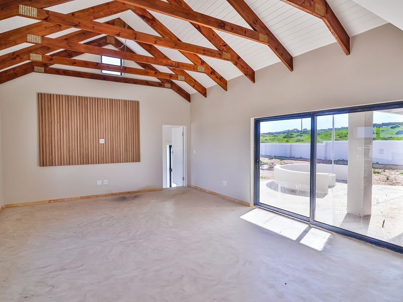 Spacious living area featuring high vaulted ceilings with exposed timber trusses, a decorative timber slat wall, and large sliding doors opening to the exterior.