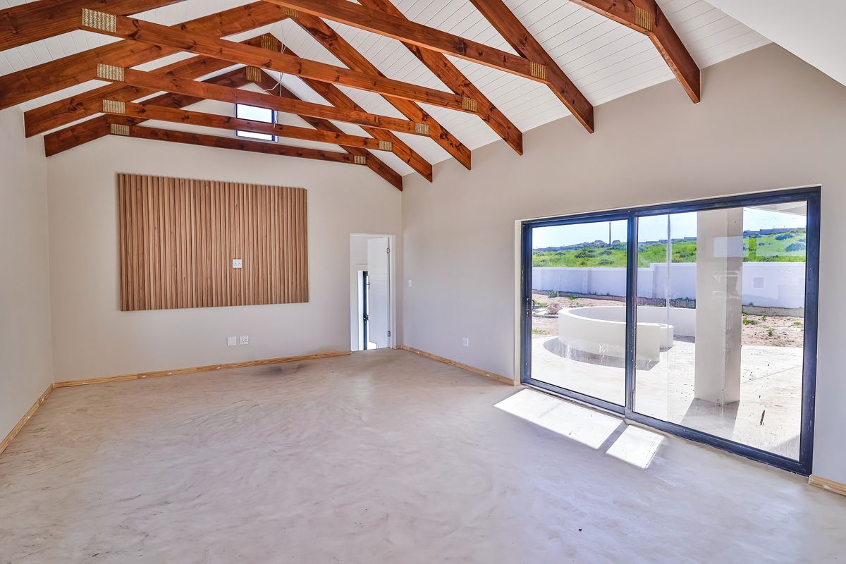 Spacious living area featuring high vaulted ceilings with exposed timber trusses, a decorative timber slat wall, and large sliding doors opening to the exterior.