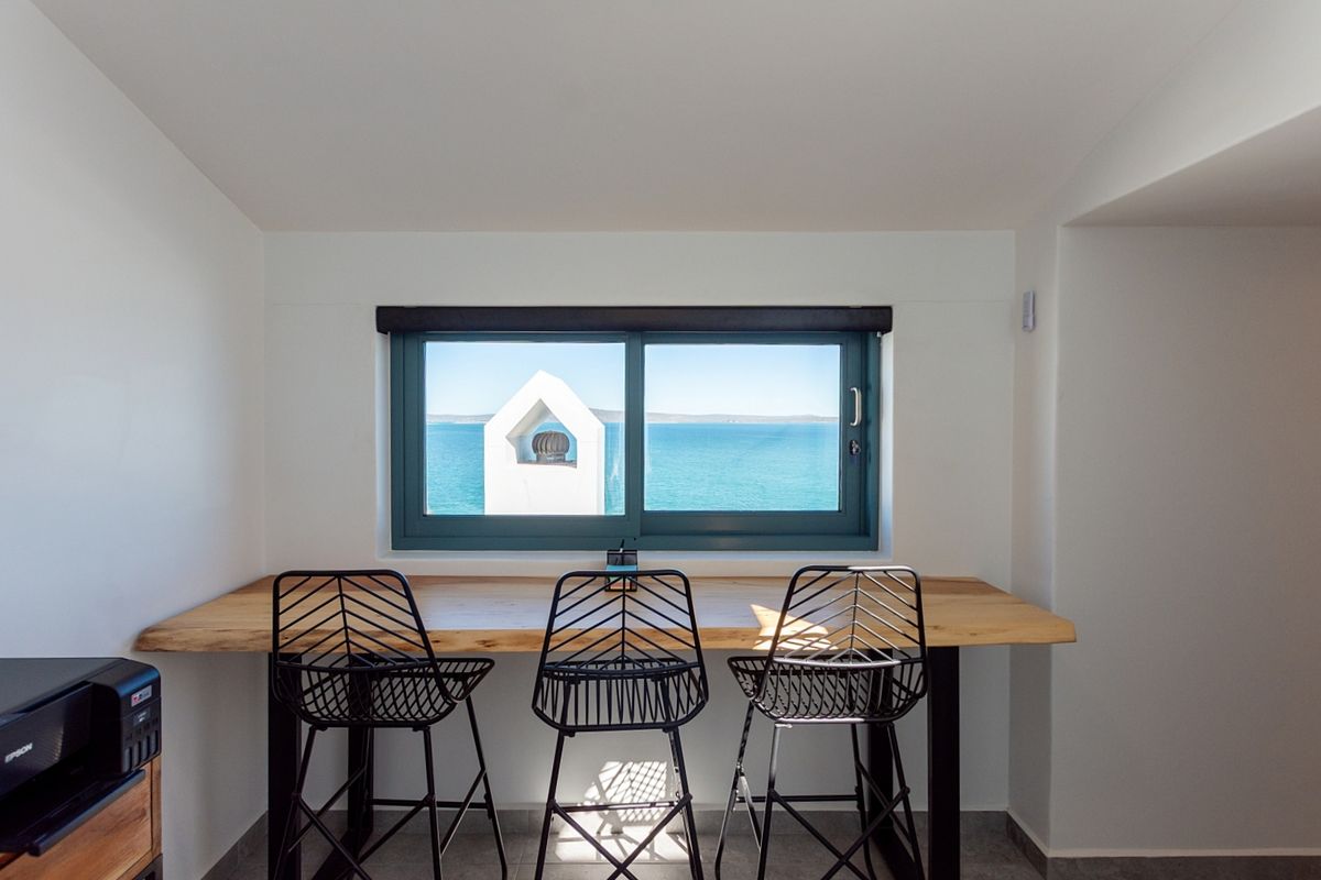 A bright living area featuring a built-in wooden desk positioned under a window with scenic ocean views.
