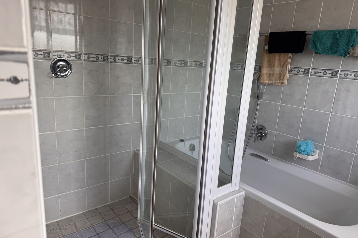 A functional bathroom featuring a separate shower enclosure and a built-in bathtub with tiled wall finishes.