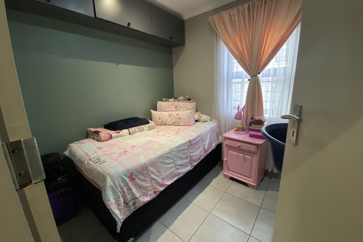 A compact bedroom featuring tiled flooring and built-in overhead storage cabinetry, providing functional space for a single bed setup.