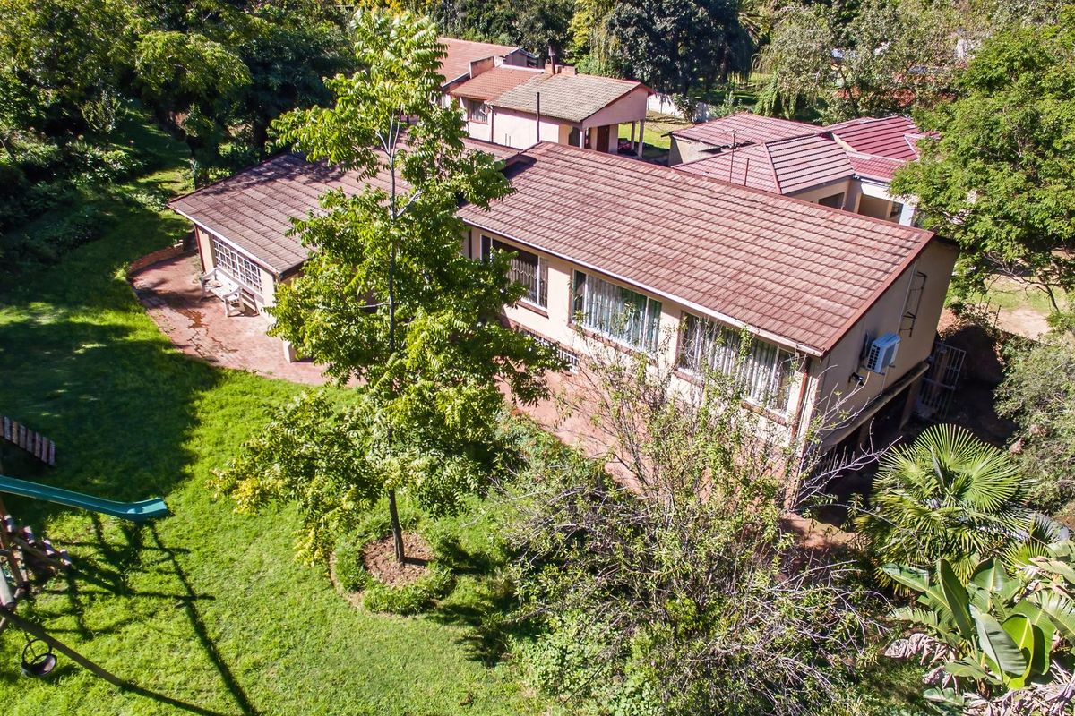 Aerial view of the property showing the tiled roof, brick exterior, and surrounding garden area with mature trees.