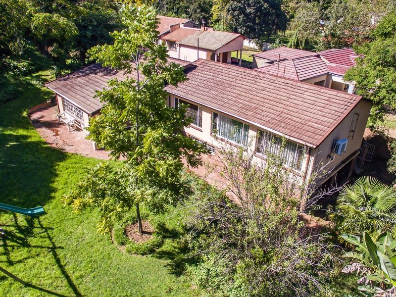 Aerial view of the property showing the tiled roof, brick exterior, and surrounding garden area with mature trees.