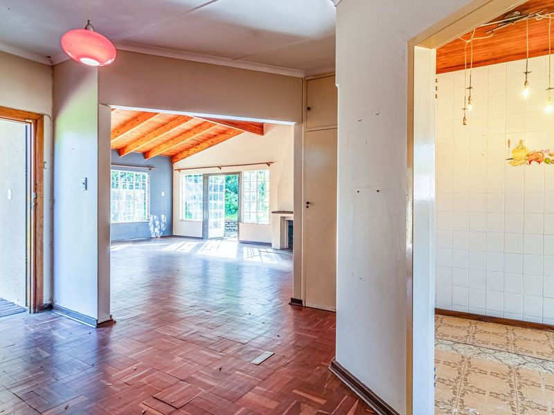 Spacious open-plan living area featuring parquet flooring, timber rafter ceilings, and direct access to an outdoor patio through french doors.