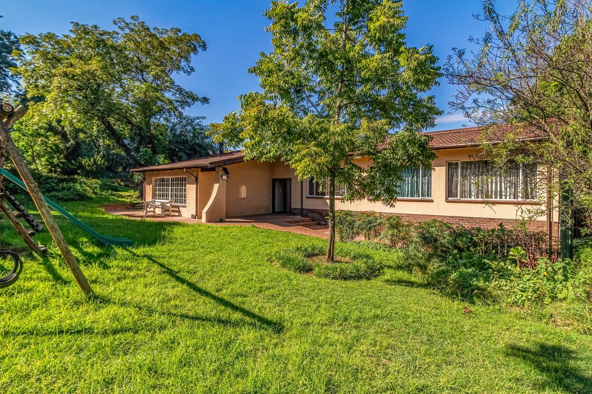Rear view of the house featuring a paved patio area, established garden, and brick and plaster exterior finishes.