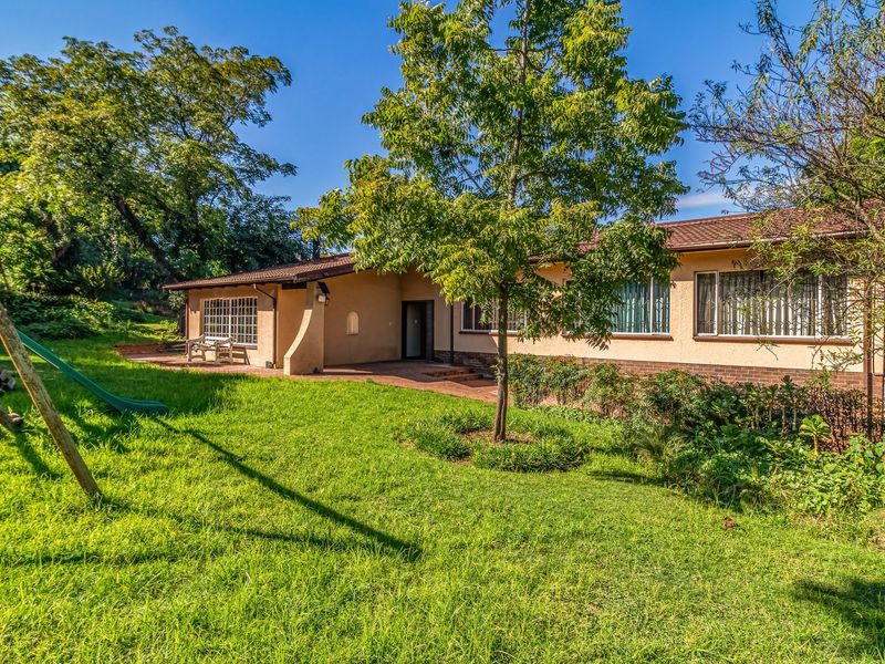 Rear view of the house featuring a paved patio area, established garden, and brick and plaster exterior finishes.